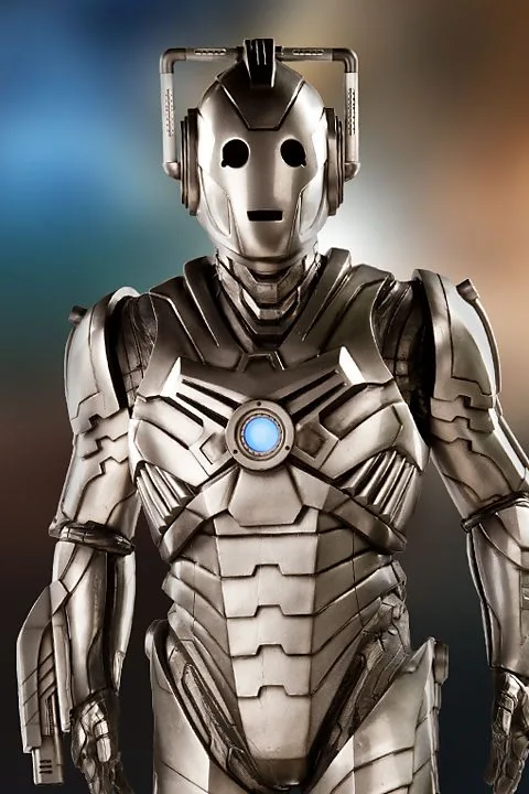 A silver, humanoid robot with a glowing blue chest light and large circular eye sockets stands against a blurred gradient…