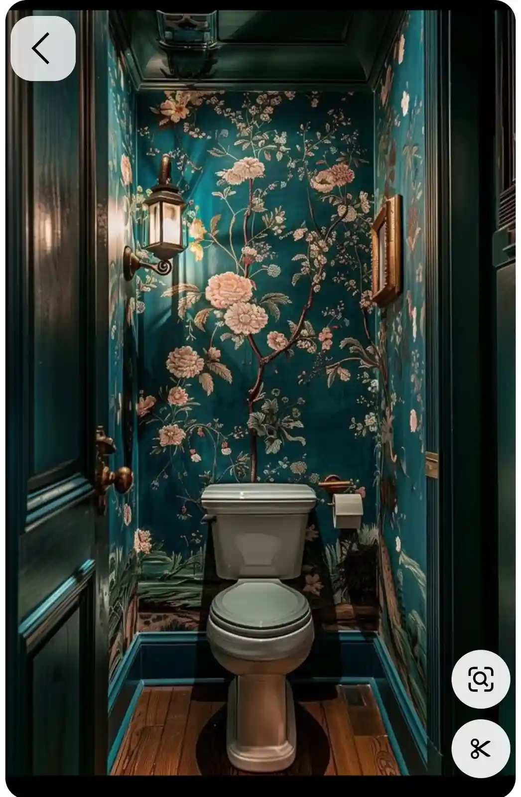 A small bathroom features a standard white toilet centered in a space with rich teal walls covered in intricate floral…