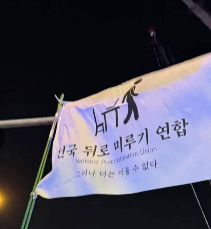 A white banner at night displays Korean text and a black silhouette of a person running away from a large 'H' symbol. The…