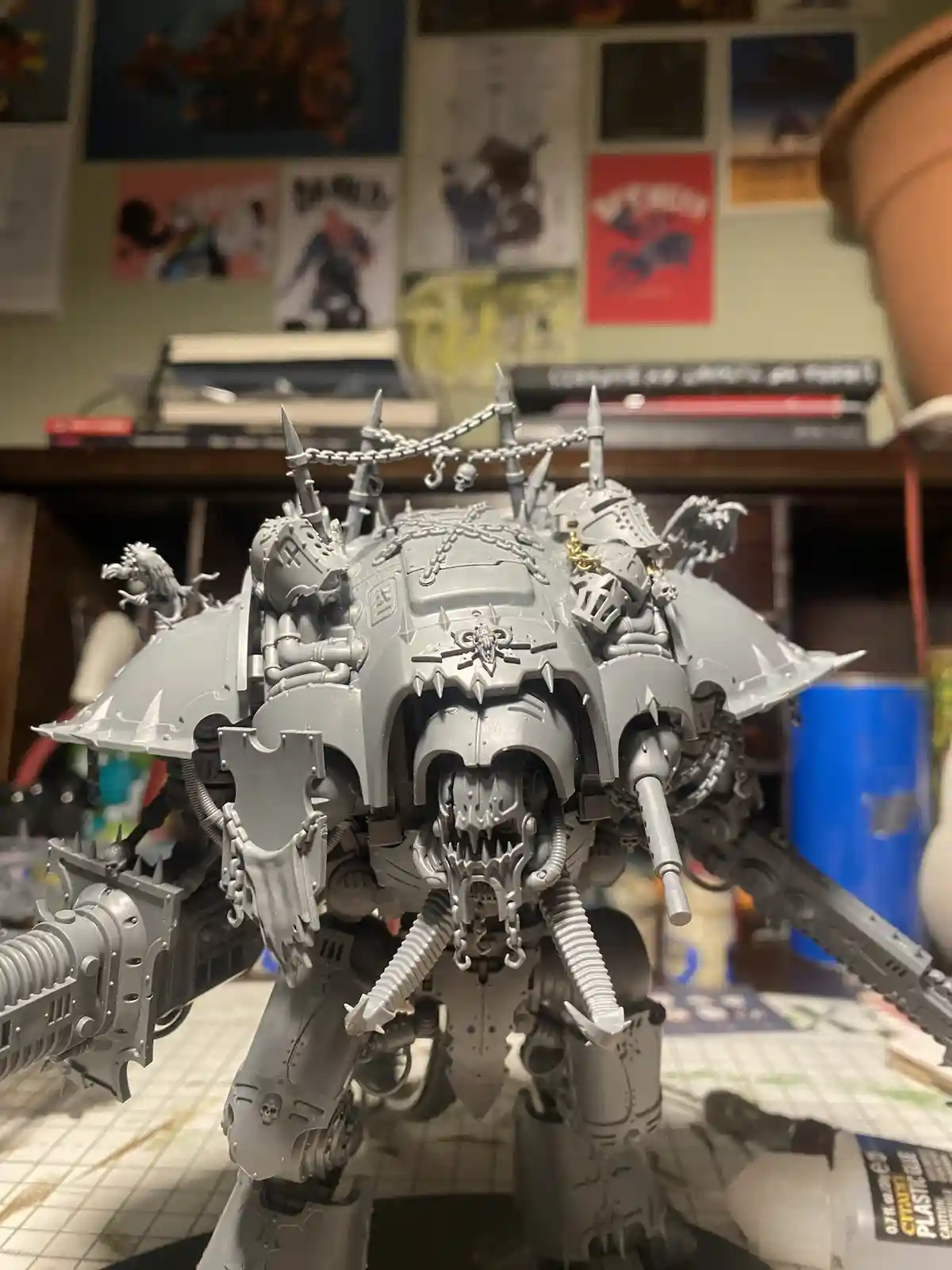 A highly detailed, unpainted grey Warhammer 40k model of a heavily armored, monstrous war machine with spikes, chains, and…