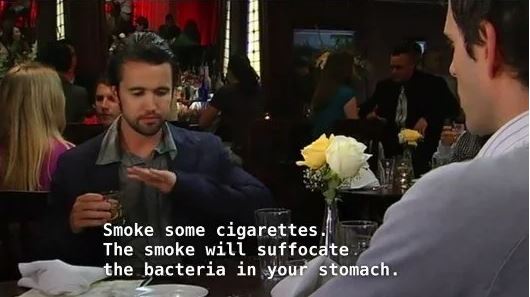 A man in a dark jacket sits at a restaurant table, gesturing with his hand while holding a glass, as if giving advice…