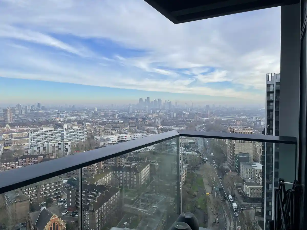 A photo taken from a high-rise balcony overlooking a sprawling cityscape with a mix of modern and traditional buildings…