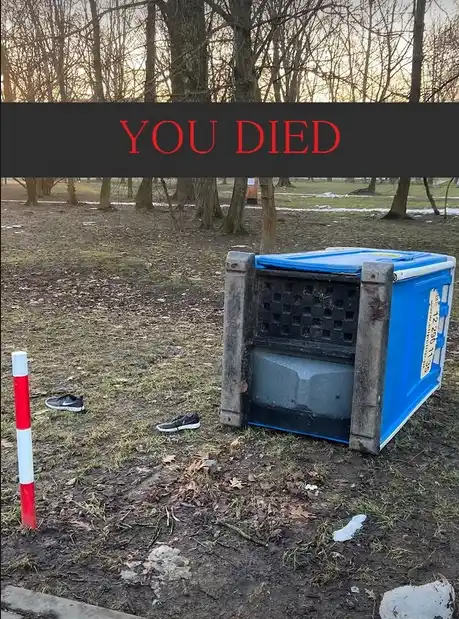 An outdoor scene shows a blue plastic animal transport crate lying on its side in muddy grass, with a red-and-white striped…