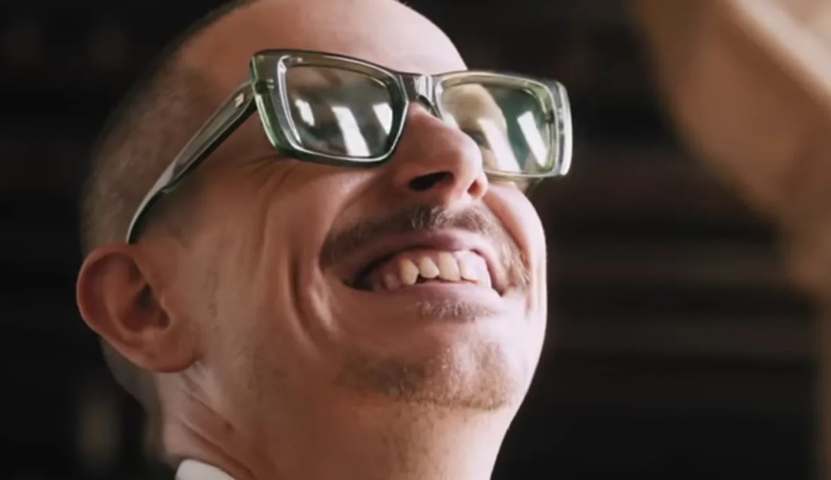 A close-up shot of a man with glasses and a mustache, laughing heartily while looking upward. The overlaid text reads 'i'm…