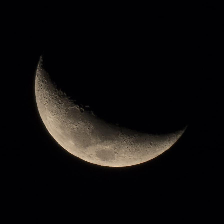 A close-up photograph of a crescent moon against a black sky, showing its cratered surface. Overlaid text reads 'i'm not…