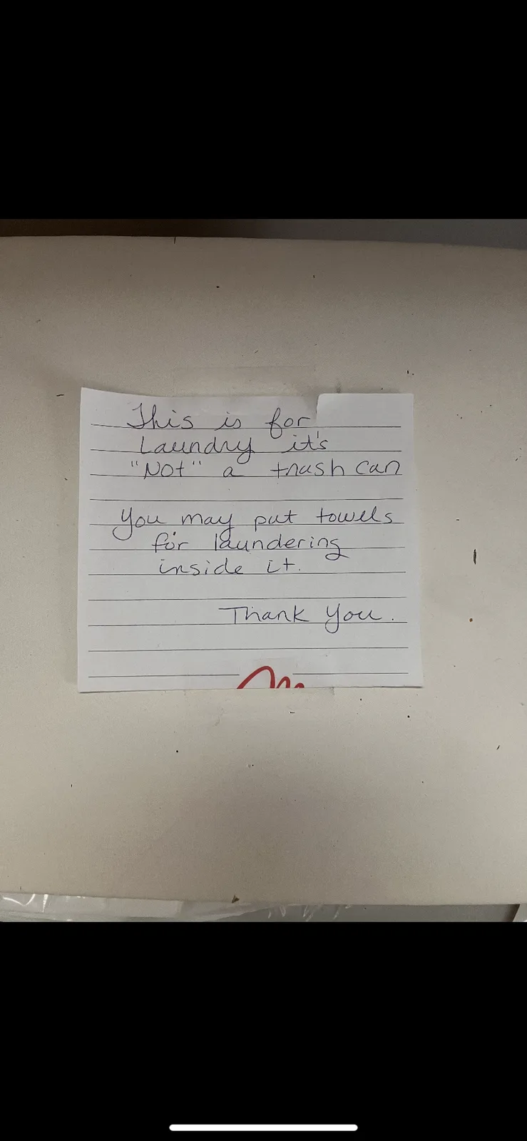 A handwritten note on lined paper taped to a beige surface, likely a bin or container, clarifies that the bin is for…