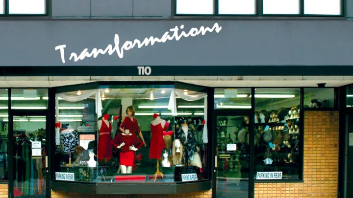 A storefront with a sign reading 'Transformations TIO' above a window display featuring mannequins dressed in red outfits…