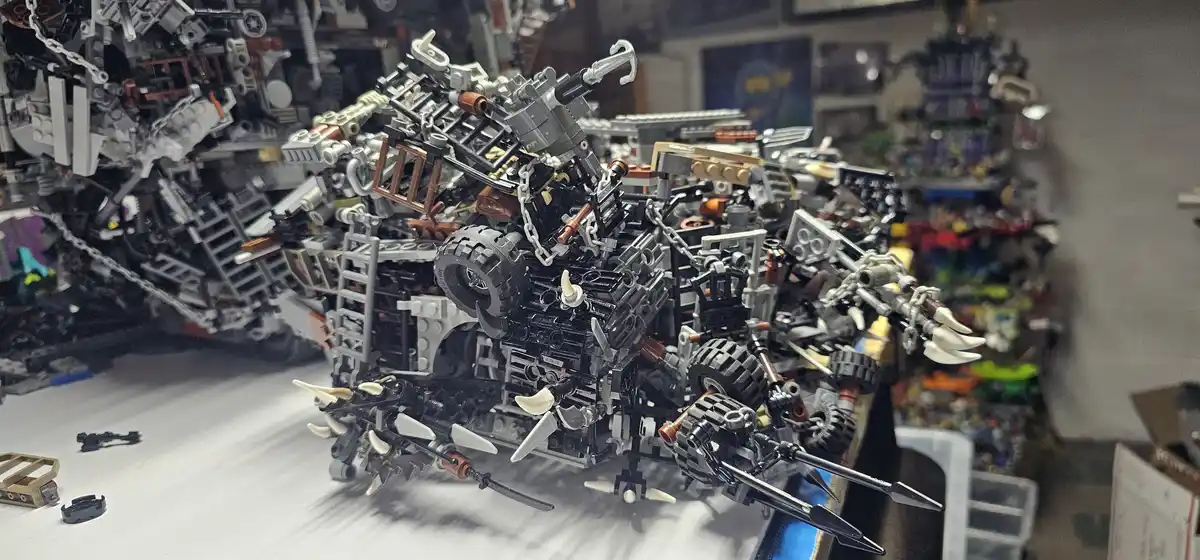 A complex, heavily modified LEGO mech model with multiple weapons, spikes, and mechanical parts, sits on a white surface in…