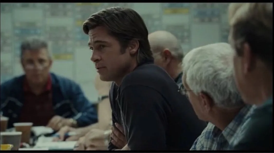 A still from the movie 'The Fighter' shows Brad Pitt looking over his shoulder with a skeptical expression while seated at a…
