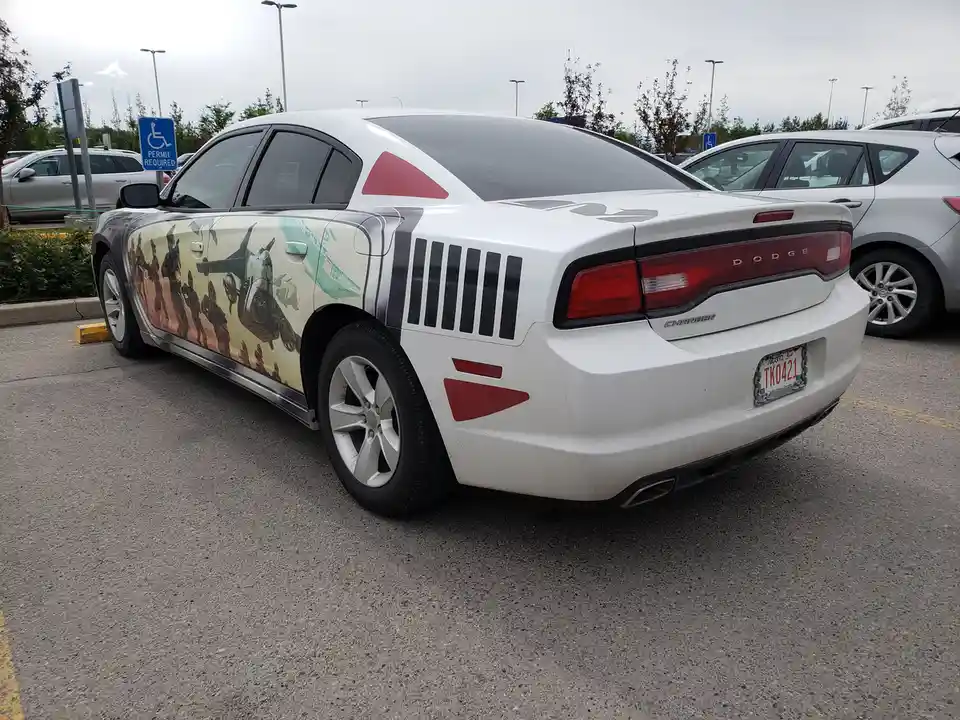a white dodge charger is parked in a handicapped parking space marked with a blue 'permit required' sign. The car's side is…
