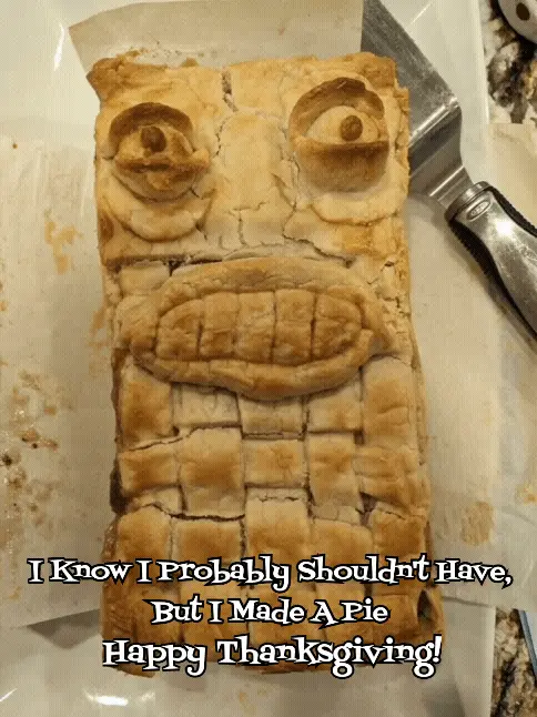 A close-up photo shows a rectangular pie with a crust shaped into a face, featuring two round eyes with raisins as pupils, a…