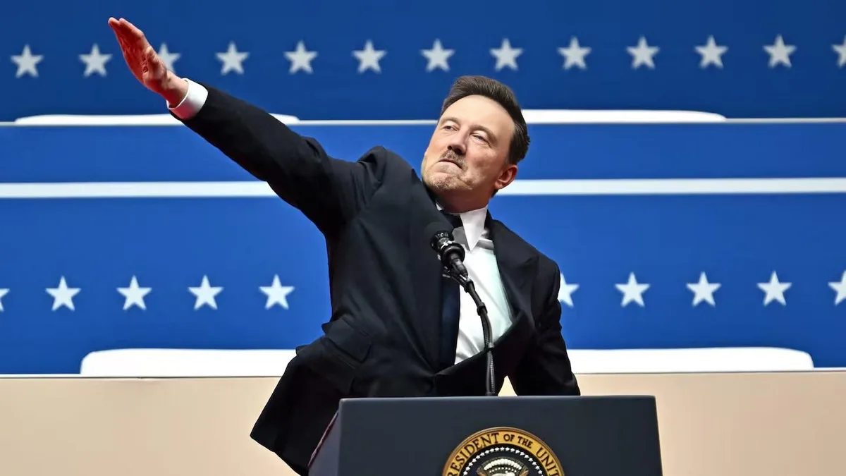 a man in a black suit and tie stands at a podium with the presidential seal, gesturing with his right arm raised against a…