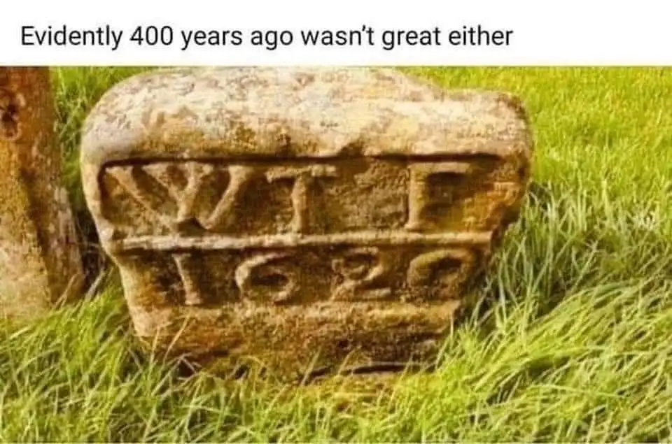A weathered, moss-covered stone marker sits in green grass, carved with the letters 'WTF' above the year '1620'. The…