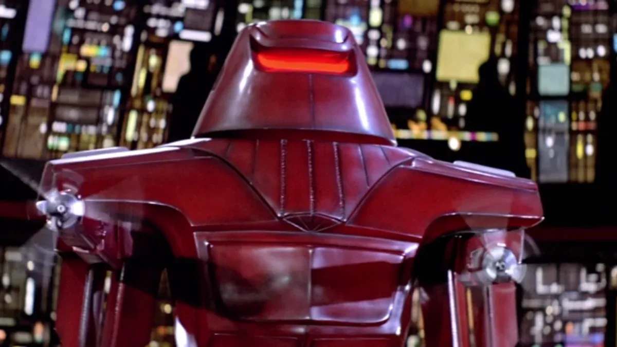 A close-up shot of the back of a red robot from the movie 'The Iron Giant', showing its shiny metallic body, glowing red…