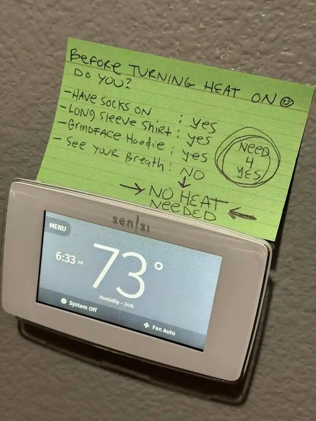 A green sticky note is taped to a white Sensi thermostat displaying 73°F and 'System Off'. The note lists four questions…
