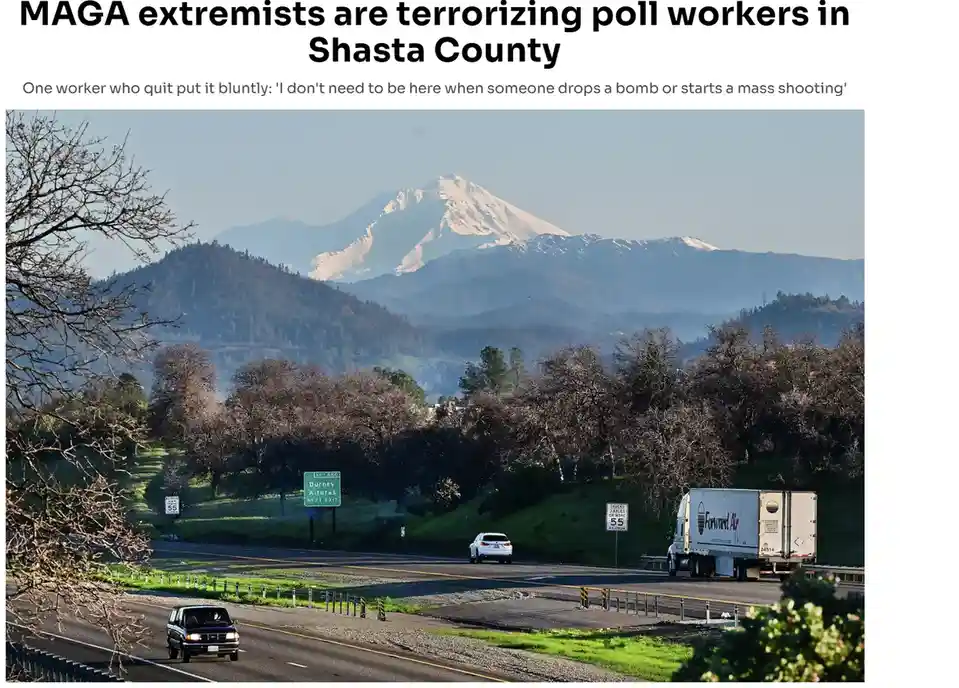 A scenic highway photo with snow-capped mountains in the background, cars and a truck on the road, and roadside signs…
