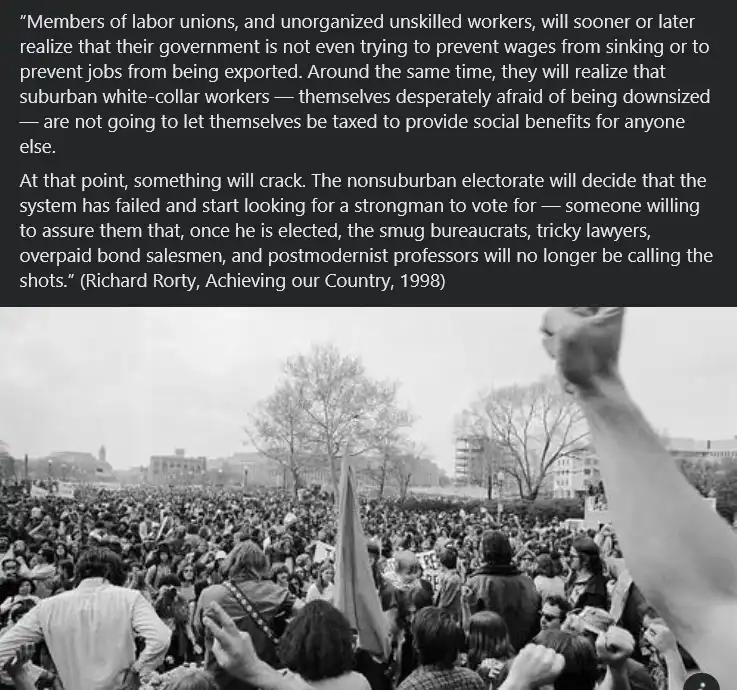 A black-and-white photo of a large, passionate protest crowd with many people raising their fists in the air, set against a…