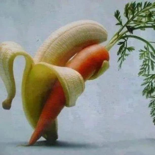 A peeled banana is positioned around a carrot, creating the illusion of a person in a banana peel costume holding a carrot…