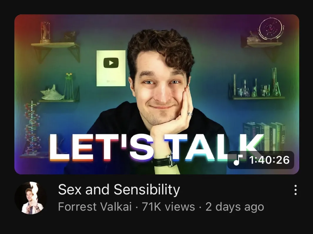 A screenshot of a YouTube video thumbnail showing a man with curly hair smiling while resting his chin on his hand. He is in…