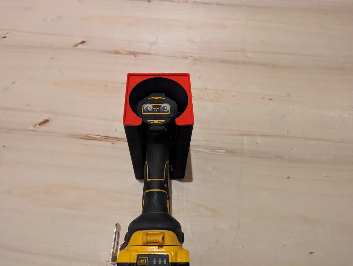 A yellow and black power tool, resembling a drill or impact driver, is shown upright in a red and black charging dock on a…