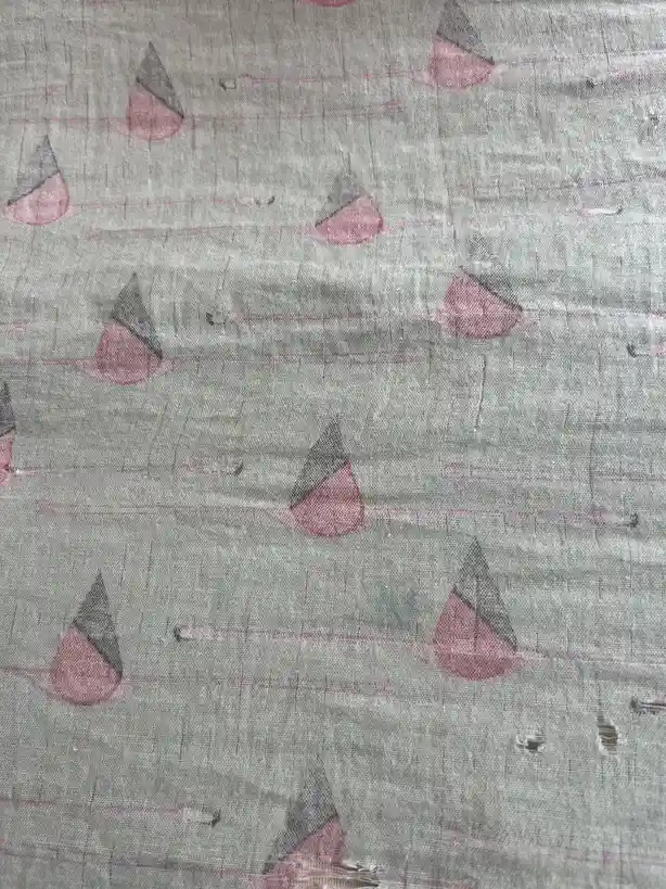 A close-up of a gray fabric with a repeating pattern of pink and gray teardrop shapes on thin pink lines, showing visible…