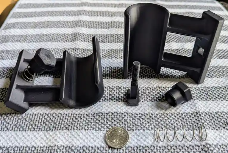 A disassembled 3d-printed object, resembling a gun, is laid out on a striped towel with its components including a bolt…