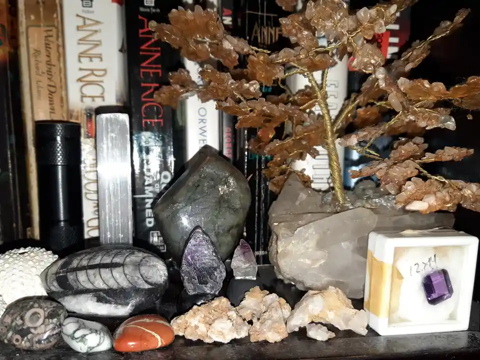 A close-up shot of a shelf displaying various crystals and minerals, including a large smoky quartz cluster on a wire frame…