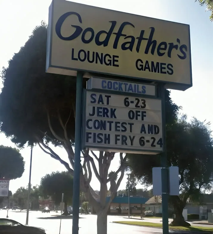 An outdoor sign for 'Godfather's Lounge Games' features a marquee board listing events: 'Cocktails', 'Sat 6-23 Jerk Off…