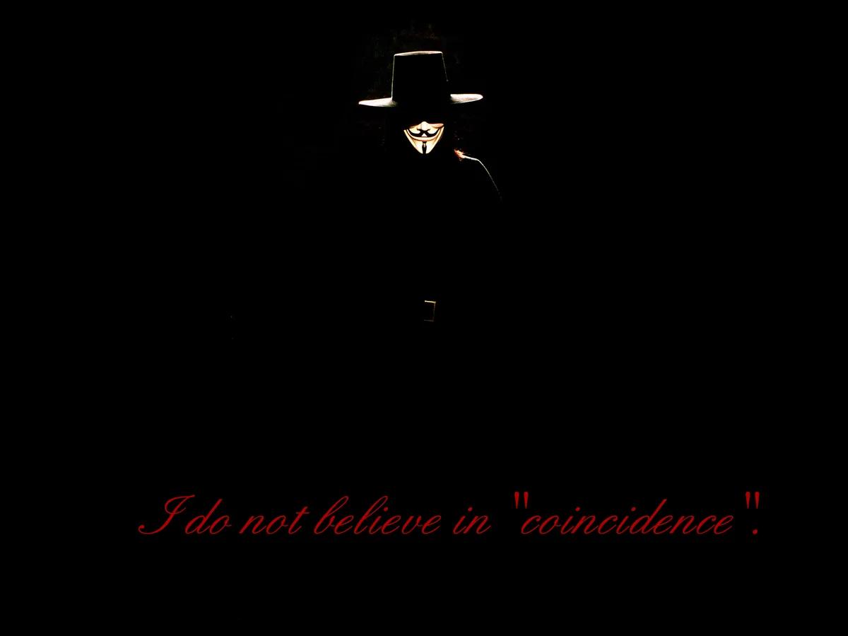 A silhouette of a person wearing a wide-brimmed hat and a Guy Fawkes mask, illuminated from behind against a black…