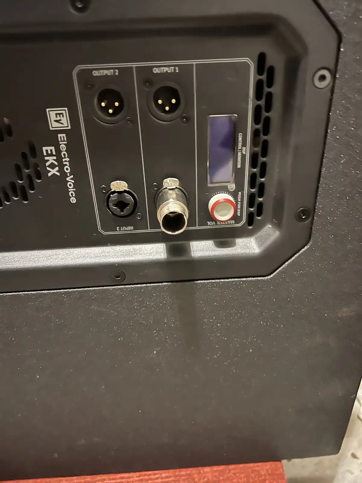 A close-up of the back panel of an Electro-Voice EKX speaker showing various audio jacks and a red-and-white rotary knob…