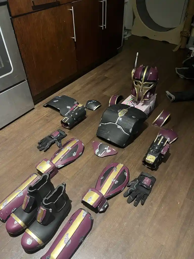 A collection of custom-made, purple and gold armored costume pieces, including a helmet, chest plate, gauntlets, boots, and…