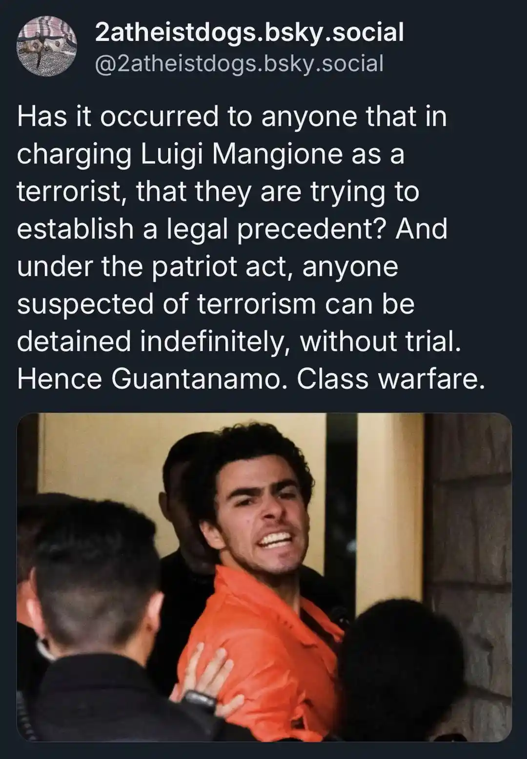 A man in an orange jumpsuit is being escorted by several people, his face contorted in an expression of extreme distress or…