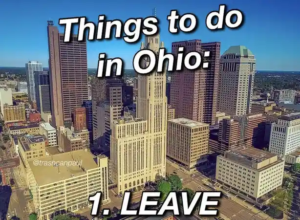 An aerial photo of a dense urban skyline with numerous tall buildings under a clear blue sky. Large white text overlaid at…