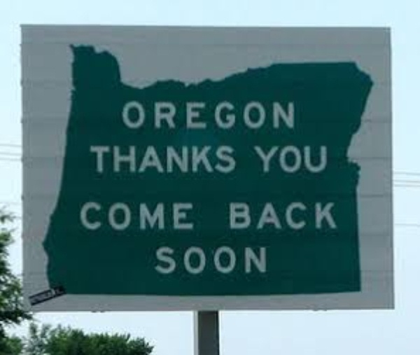 A large green billboard shaped like the state of Oregon displays the message 'OREGON THANKS YOU COME BACK SOON' in white…