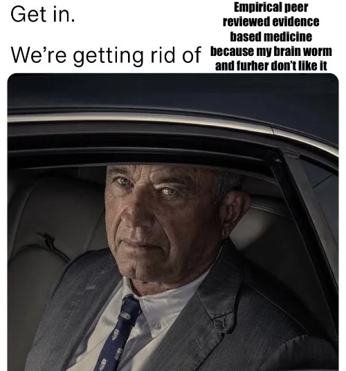 A man in a suit and tie sits in the driver's seat of a car, looking sternly at the viewer. Text overlaid on the image reads…