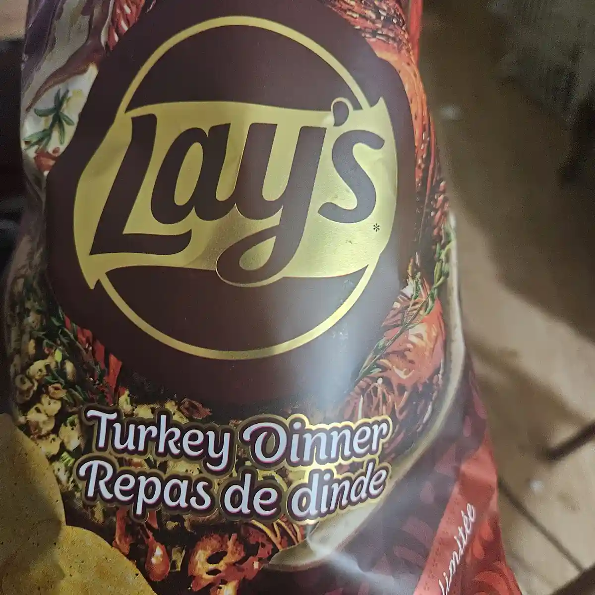 A close-up of a Lay's potato chip bag featuring the brand logo and the product name 'Turkey Dinner' with its French…
