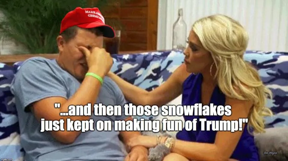 A man wearing a red 'Make America Great Again' cap sits on a blue camouflage-patterned couch, visibly distressed and wiping…