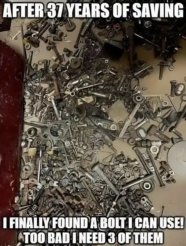 An overhead shot shows a large, messy pile of assorted rusty and worn metal hardware, including bolts, nuts, washers, and…