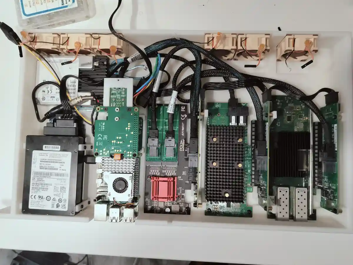 An overhead shot of a white plastic enclosure filled with various computer hardware components including circuit boards…