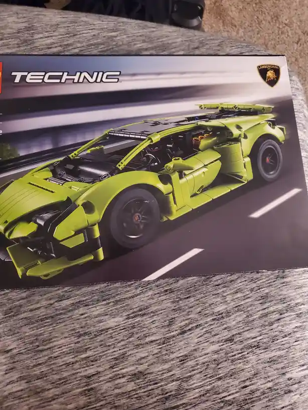 A close-up photo of a LEGO Technic Lamborghini box, showing the bright green toy car model with its hood and doors open to…
