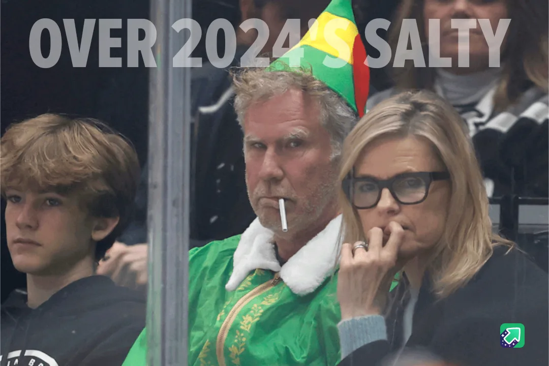 A man in a green jacket and party hat with a cigarette in his mouth sits beside a woman with glasses biting her nails, both…