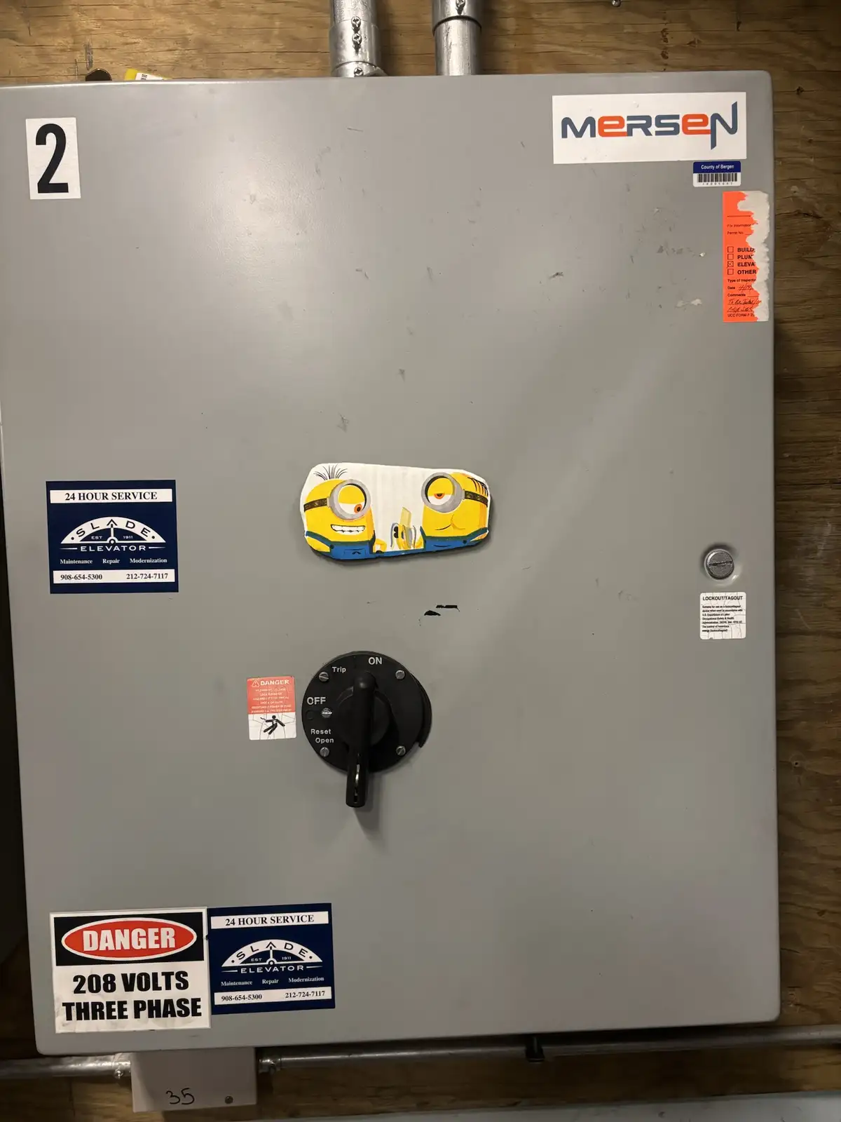 A gray industrial electrical panel with a black toggle switch labeled 'OFF', 'ON', 'Trip', 'Reset', and 'Open'. A cartoon…