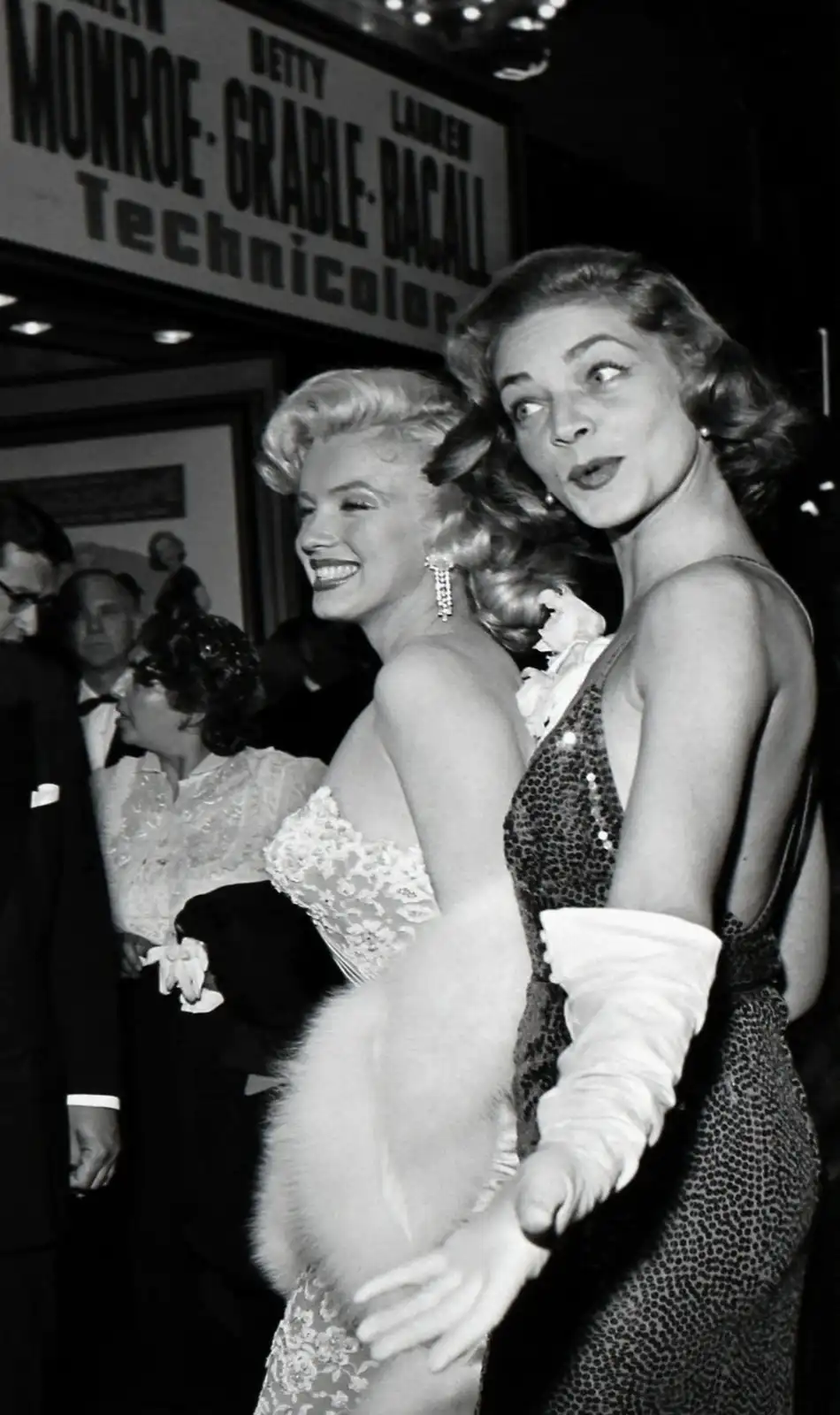 A black-and-white photo shows two glamorous women, Marilyn Monroe and Lauren Bacall, at what appears to be a movie premiere…