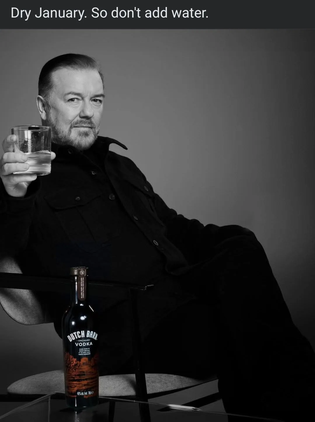 A black-and-white photo shows a man in a dark jacket sitting in a chair, holding a glass of clear liquid. A bottle of Dutch…