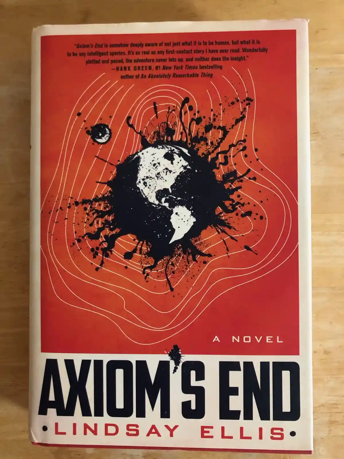 The image shows the cover of the novel 'Axiom's End' by Lindsay Ellis, featuring a red background with white concentric…