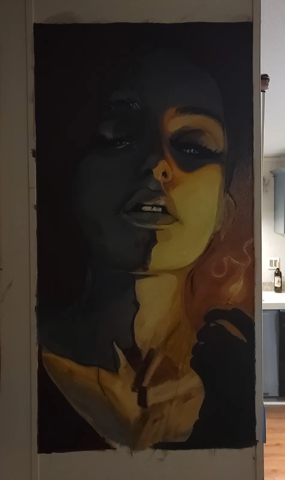 A large, unfinished painting of a woman's face and upper torso is painted directly onto a white interior door. The artwork…
