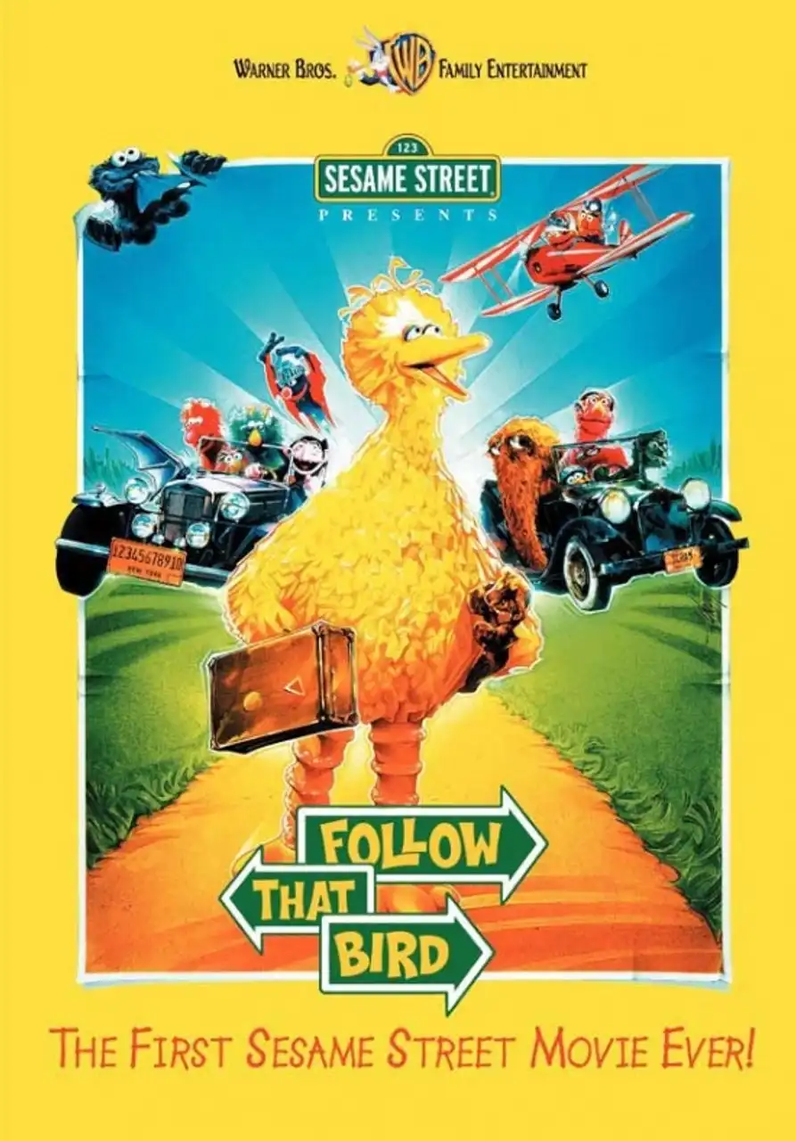 A movie poster for 'Sesame Street Presents: Follow That Bird' shows Big Bird walking down a yellow road holding a suitcase…