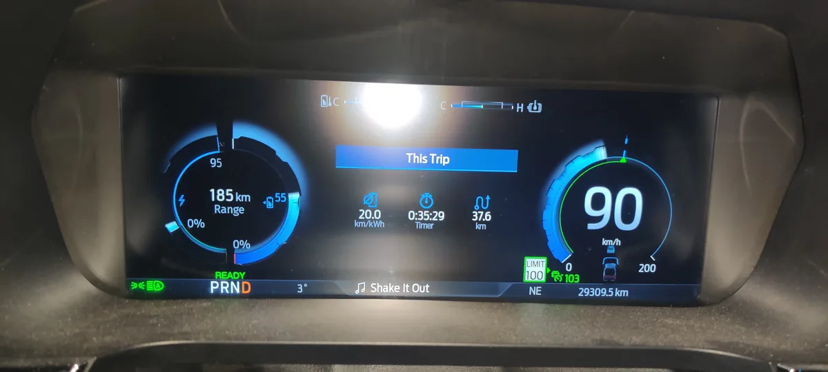 A car's digital dashboard shows a speed of 90 km/h, a range of 185 km, and a trip timer of 0:35:29. The speed limit is set…