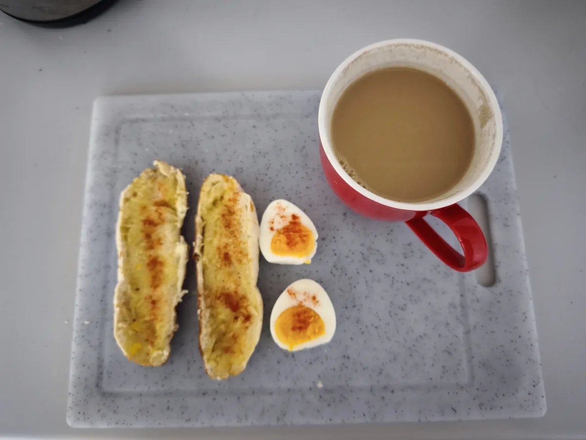 An overhead shot of a simple breakfast on a speckled gray plate: two slices of toasted bread, two halves of a hard-boiled…