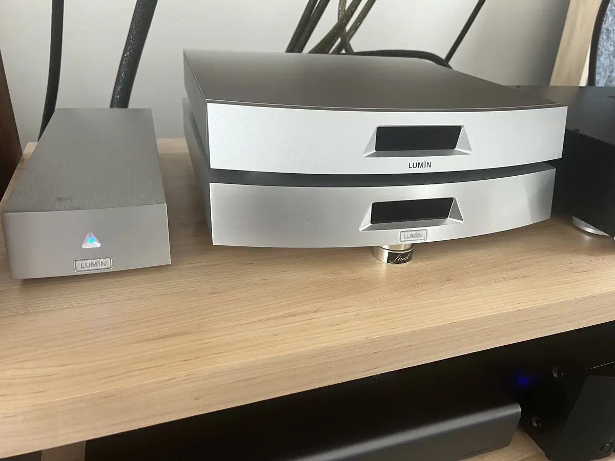 Two silver Lumin audio components sit on a wooden shelf; the larger unit has a glowing blue power indicator and a 'final'…